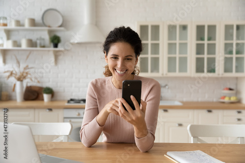 Photography Excited woman holding smartphone, chatting online in modern kitchen at home, loo
