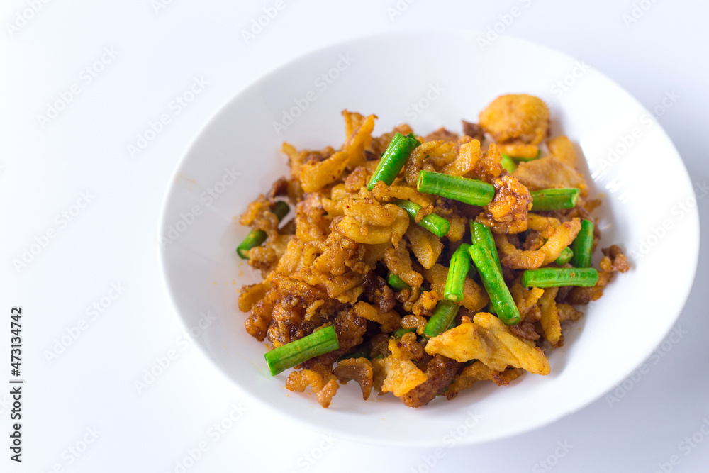Stir fried crispy pork and yardlong bean with Thai spicy curry paste on white plate in Thai food style. Stir fried crispy pork and yardlong bean with Thai spicy curry paste on white plate in Thai food style.