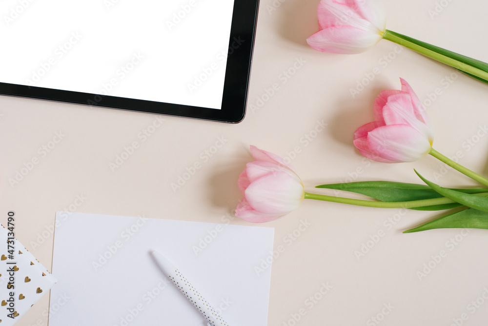Obraz premium Spring background flat lay of pink tulips with tablet mockup, copy space for text. Mother's Day or Valentine's Day