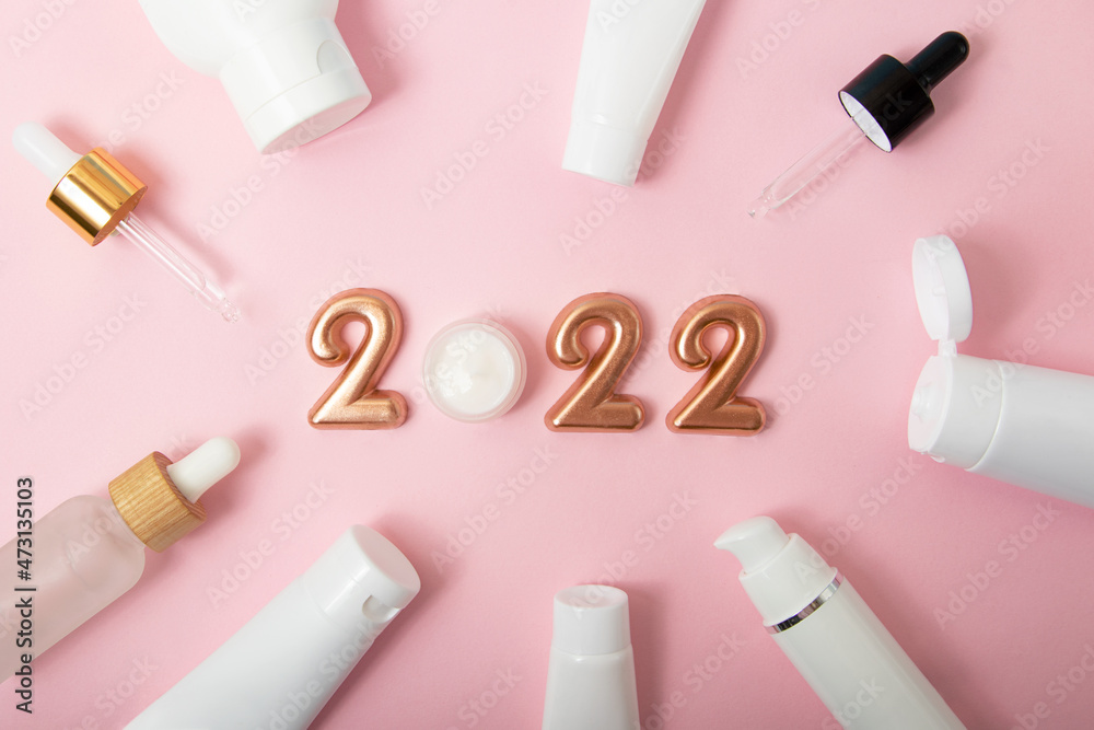 Top view of the cosmetics containers on pink background.Rose gold numbers 2022 above.Good for new year offer and text overlay. Top view of the cosmetics containers on pink background.Rose gold numbers 2022 above.Good for new year offer and text overlay.