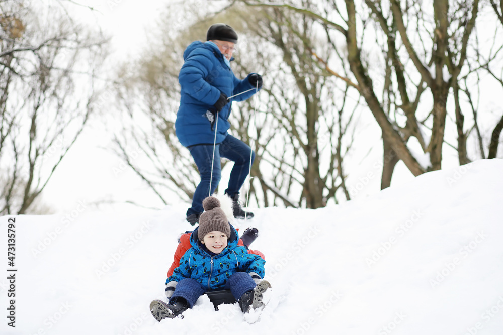 Children in the park in winter. Kids play with snow on the playground. They sculpt snowmen and slide down the hills.