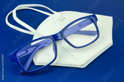 Corona Pandemie FFP2 Schutzmaske und Brille auf blauem Hintergrund