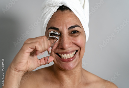 Happy Latin mature woman using eyelash curler - People beauty and wellness lifestyle concept