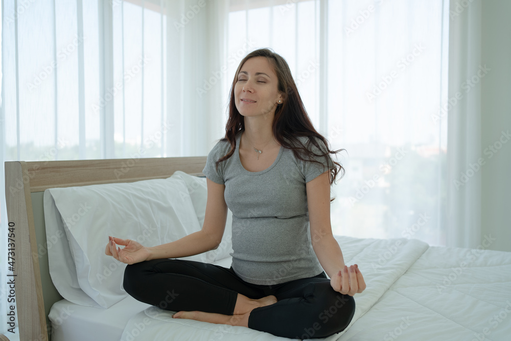 Portrait of Mature Pregnant Woman Doing Meditation in Bedroom at Home