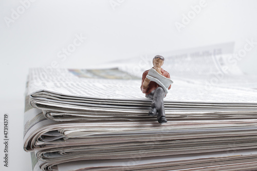 a figure of a man reading a newspaper while on a full size newspaper photo