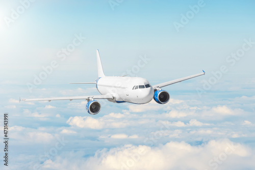 Airplane flying in blue sky above the clouds, travel by plane, international flight.