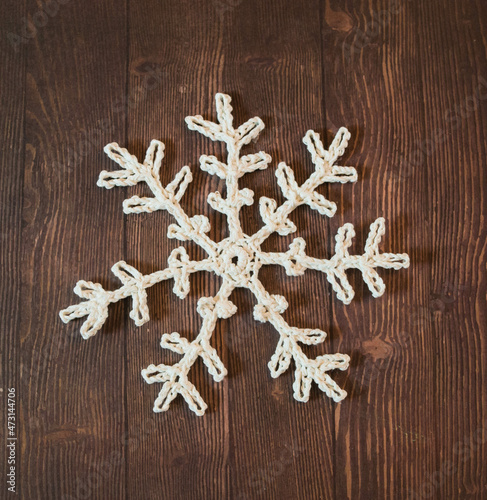 big white crochet snowflake on dark brwon wooden ground