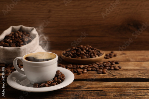 Cup of aromatic hot coffee and beans on wooden table, space for text © New Africa