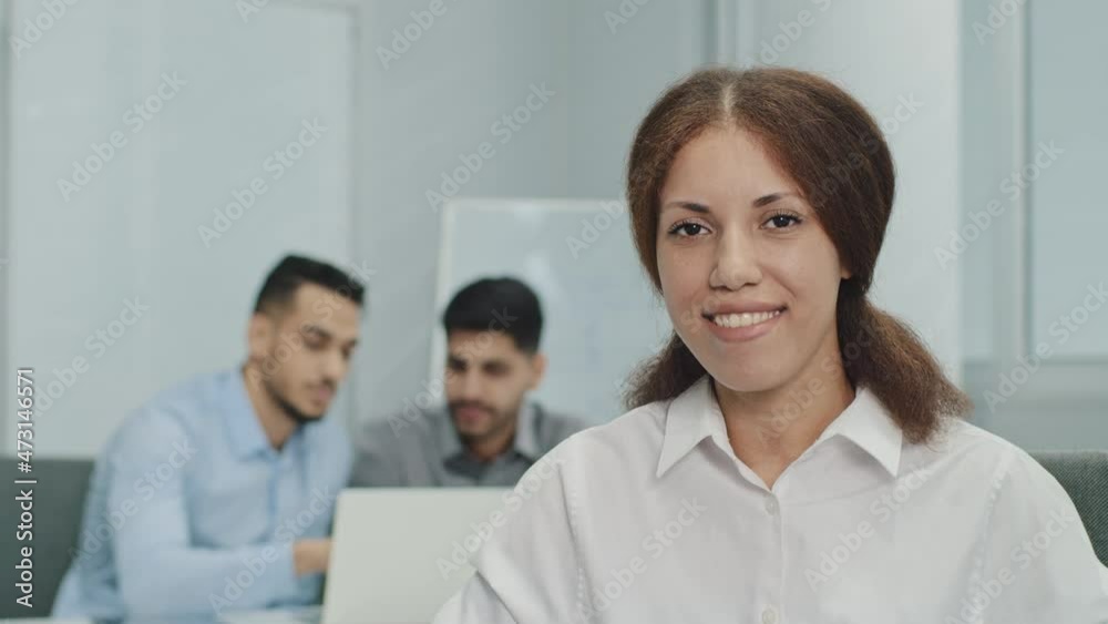 Smiling female leader manager coach speaker looking at camera, waving hello. Friendly businesswoman greeting or welcoming new worker in modern business office with multicultural professionals team Smiling female leader manager coach speaker looking at camera, waving hello. Friendly businesswoman greeting or welcoming new worker in modern business office with multicultural professionals team