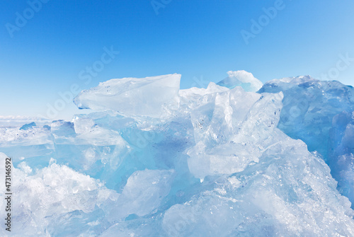 Chunks of transparent blue ice on a sunny day against the backdrop of a clear blue sky. Natural cold background. Travels on the frozen Baikal Lake. Winter landscape