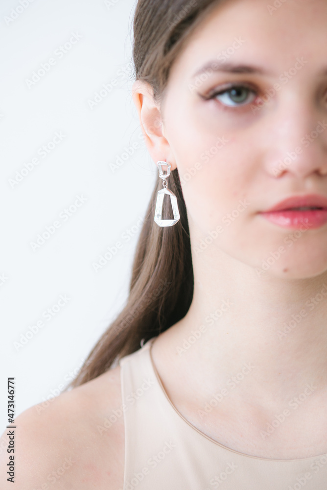 Trendy silver earrings on a beautiful young girl with long dark hair. Beauty and fashion Trendy silver earrings on a beautiful young girl with long dark hair. Beauty and fashion
