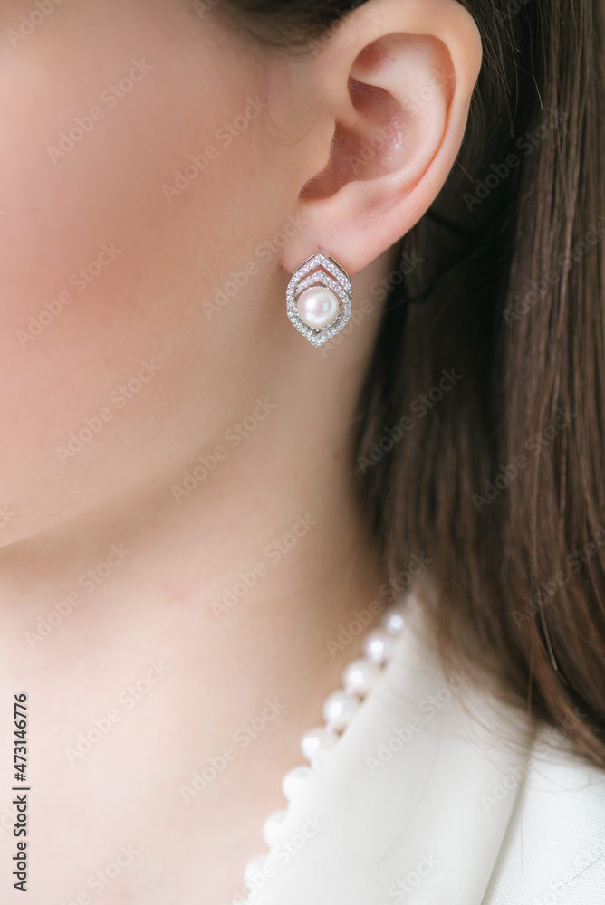 Trendy silver earrings  on a beautiful young girl with long dark hair. Beauty and fashion 