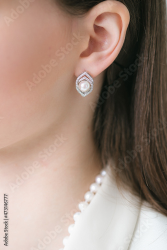Trendy silver earrings  on a beautiful young girl with long dark hair. Beauty and fashion 