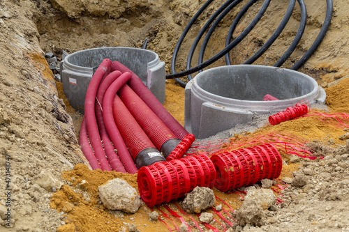 Gros plan sur un regard de visite en béton pour le raccordement et la distribution de gaines rouges électriques