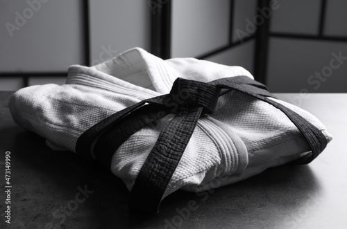 Martial arts uniform with black belt on grey stone table indoors photo