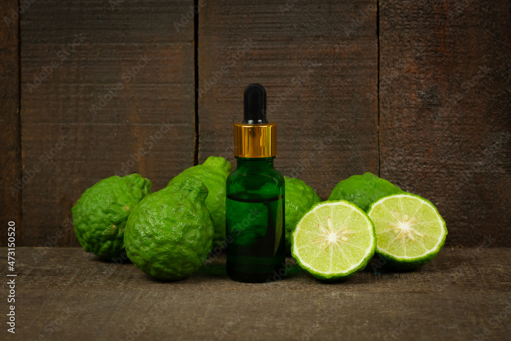 Bergamot oil in green bottle and fresh bergamot fruit on rustic wooden background. Bergamot oil in green bottle and fresh bergamot fruit on rustic wooden background.