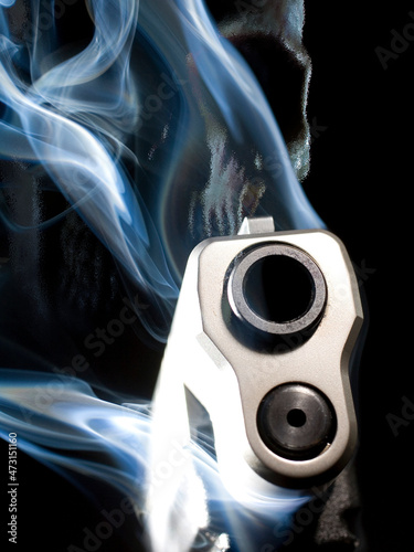 3D illustration of a smoking ghost gun with a skull behind