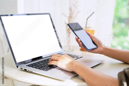 Young woman sitting and working on laptop and smart phone at coffee shop © Kittiphan