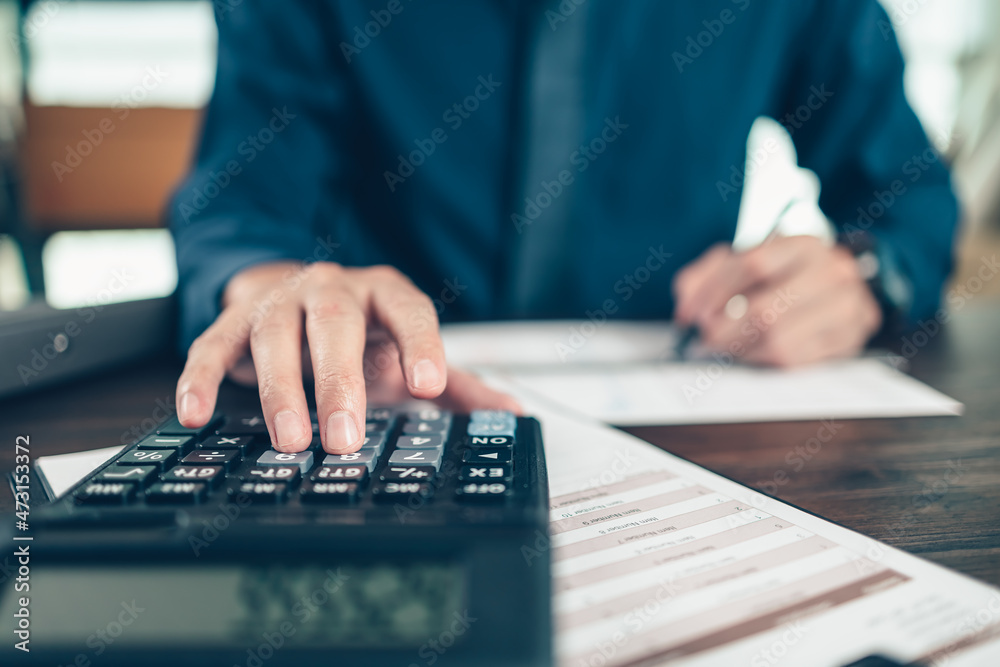 Financial businessman working on desk office using a calculator to calculate calculating corporate income tax data And analyzing charts of financial. finance and accounting concept. Financial businessman working on desk office using a calculator to calculate calculating corporate income tax data And analyzing charts of financial. finance and accounting concept.