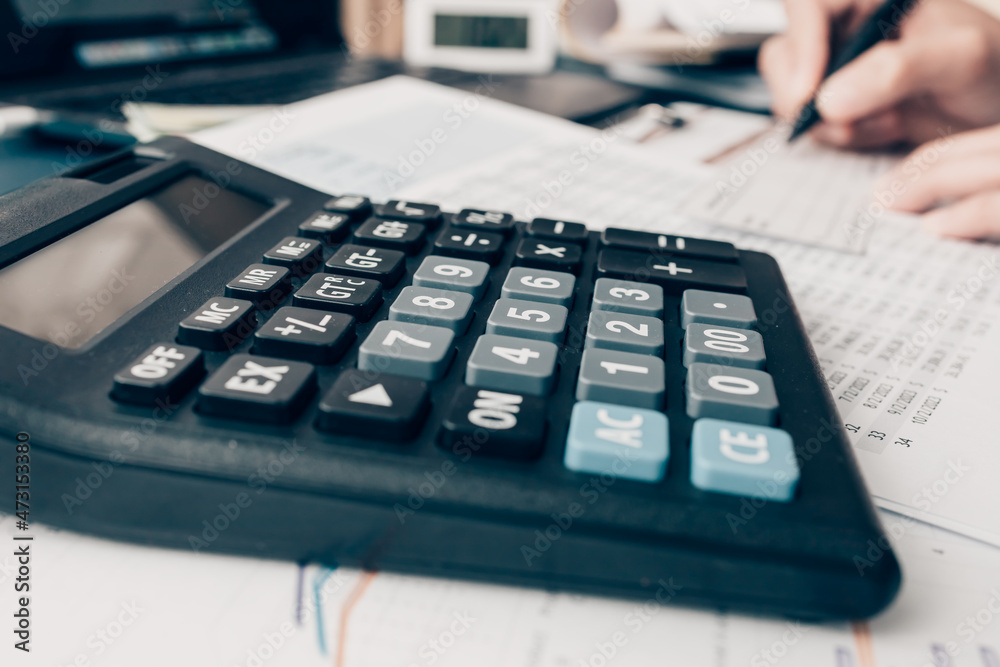 Financial businessman working on desk office using a calculator to calculate calculating corporate income tax data And analyzing charts of financial. finance and accounting concept. Financial businessman working on desk office using a calculator to calculate calculating corporate income tax data And analyzing charts of financial. finance and accounting concept.