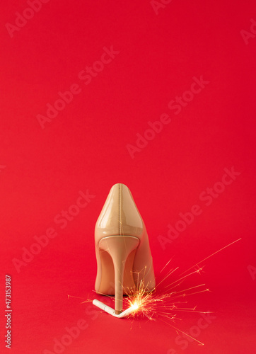 Creative idea made of high heel shoe and cigarette with sprklers against red background. Minimal celebration New Year or Chriistmas party concept. Copy space. photo