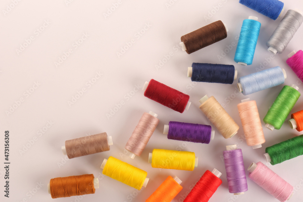 Set of colorful sewing threads on white background, top view Set of colorful sewing threads on white background, top view