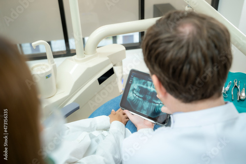 Dentist and patient commenting treatments in a tablet application in a consultation,Dentist and patient in dentist office.