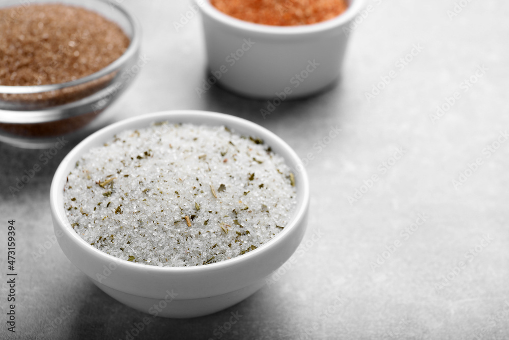 Different kinds of salt in bowls on grey table, space for text Different kinds of salt in bowls on grey table, space for text