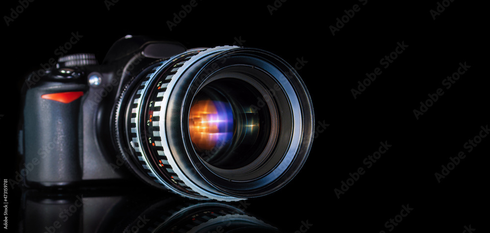modern DSLR camera and retro telephoto lens close up on black background with reflection