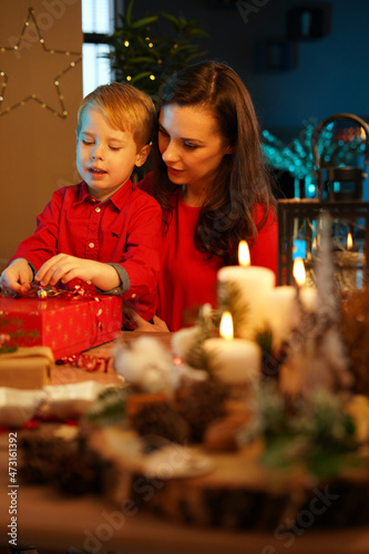 Cheerful mother packing christmas presents with her son
