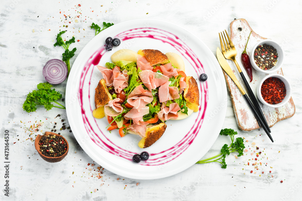 Prosciutto salad, brie cheese and vegetables on a white plate. Top view. Rustic style. Prosciutto salad, brie cheese and vegetables on a white plate. Top view. Rustic style.