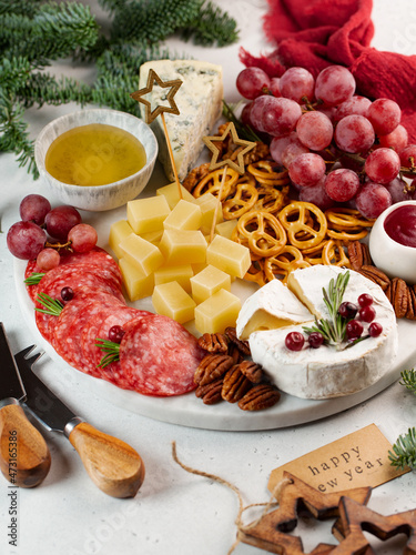 Soft focus, antipasti with cheese, sausage, nuts, cracker, honey, on a round marble tray, vertical, new year party