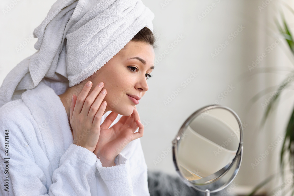 Portrait of a young beautiful woman wearing a bathrobe at home. doing her daily skincare routine with natural cosmetics Portrait of a young beautiful woman wearing a bathrobe at home. doing her daily skincare routine with natural cosmetics