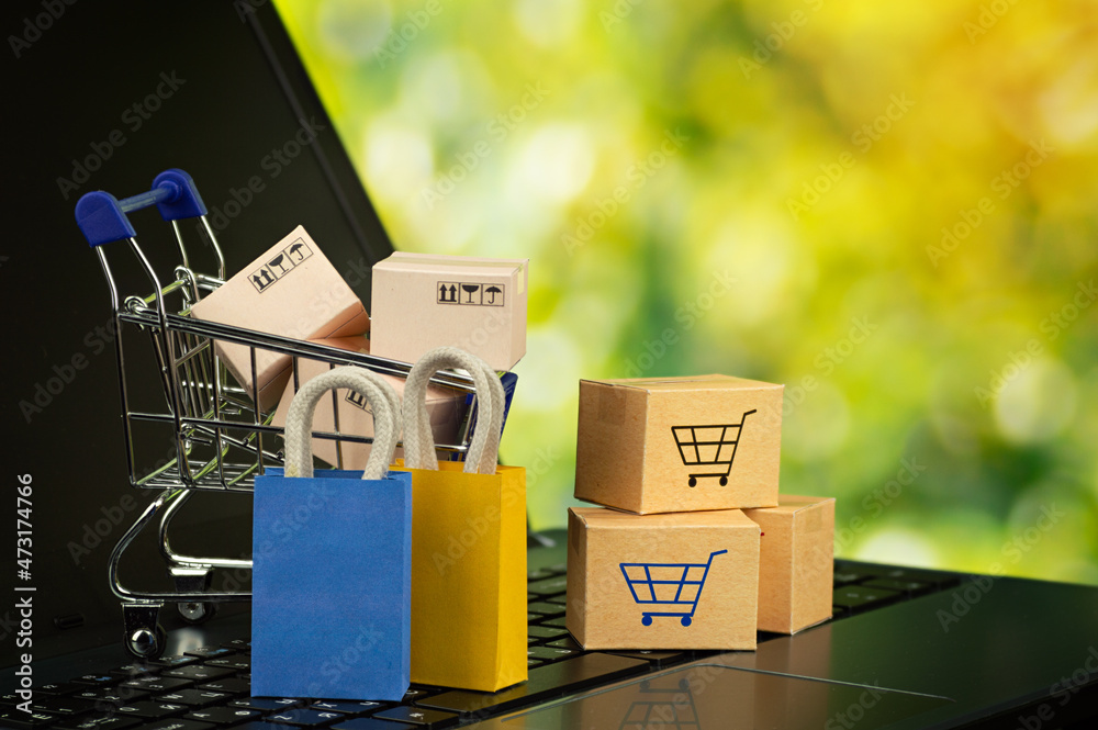 Online shopping or delivery service concept shopping bag with cardboard boxes in trolley on laptop keyboard service online web sites Customer can buy everything from office or home.