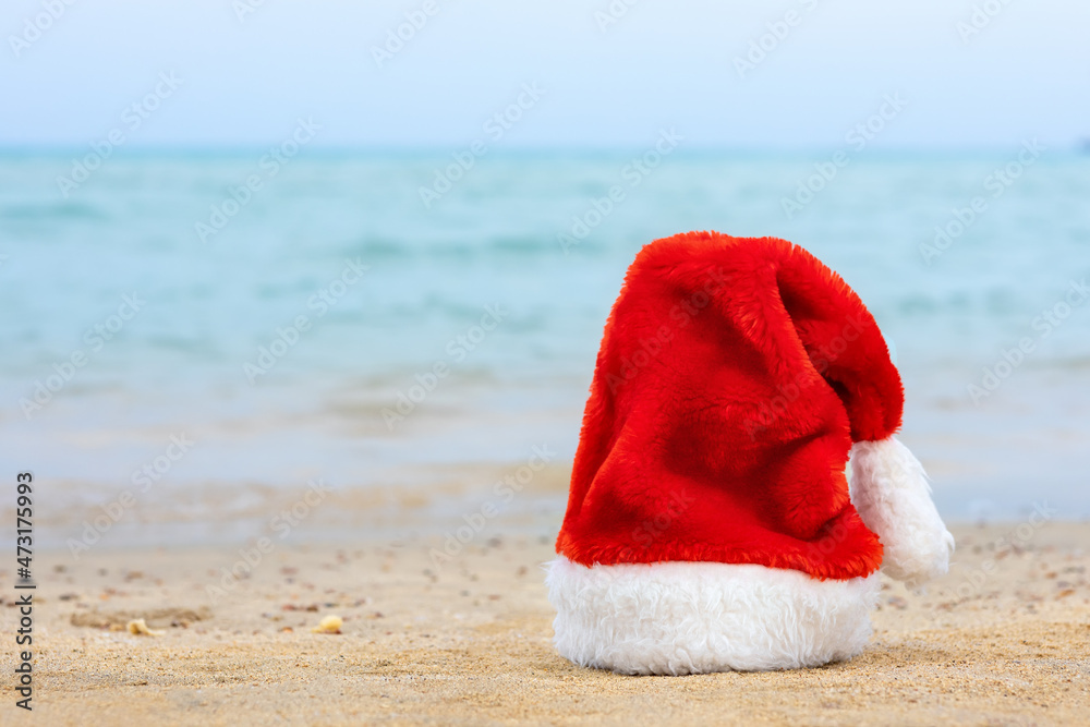 Santa hat on sandy beach. Concept of celebrating christmas Santa hat on sandy beach. Concept of celebrating christmas