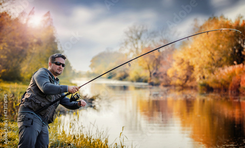 Angler enjoys in fight with a big fish on the river. Sport and recreation concept