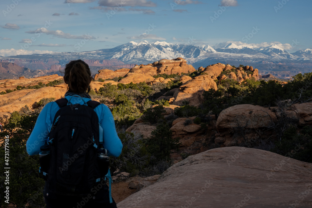 Hiker Looks Out Over Devils Garden Loop and La Sal Mountains In The Distance