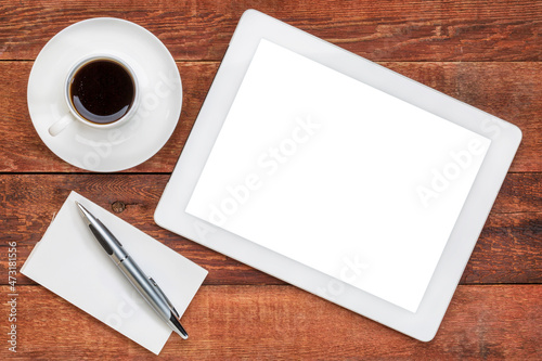 mockup of digital tablet with a blank isolated screen (clipping path included) with a cup of coffee against rustic, weathered wooden table