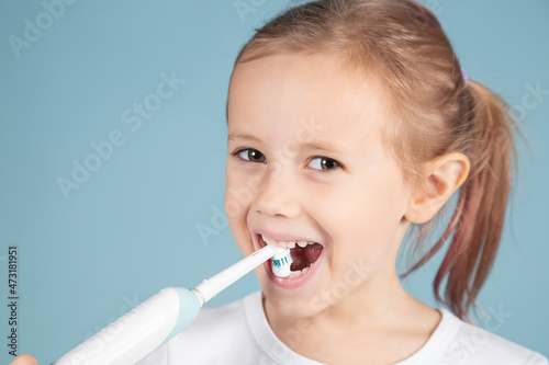 Portrait of cute little girl brushing teeth Standing Over blue Background