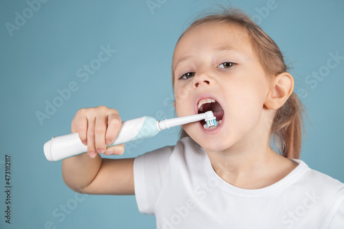 Smiling little caucasian girl brushing teeth Standing Over blue Background
