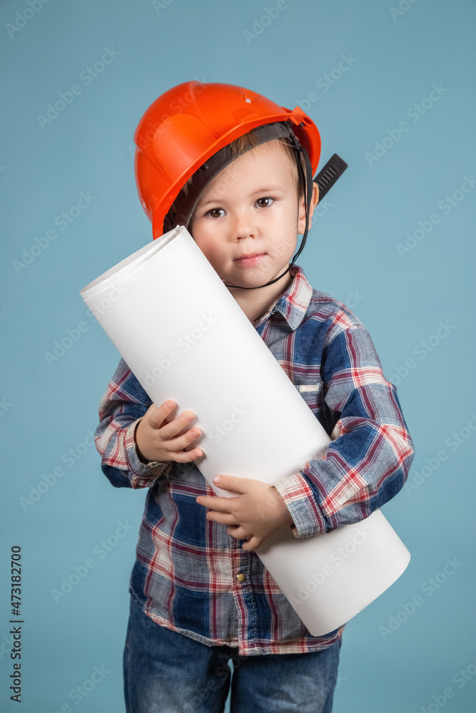 Portrait of adorable boy builder in hardhats holding construction drawing