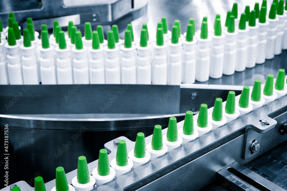 Close-up Many white plastic spray bottles for packaging liquid medicines or cosmetics in a row on a conveyor belt in a pharmaceutical manufacturing factory