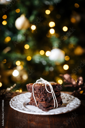 Chocolate brownies wrapped in group as a present in front of Christmas tree with Christmas lights in festive atmosphere and decoration