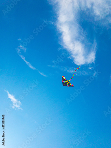 Kite background. Colorful high flying toy. Air kite fly on blue wind sky. Rainbow kite in summer clouds. Festive, happiness, success background.