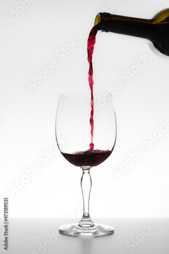 Red wine falling in glass on white background