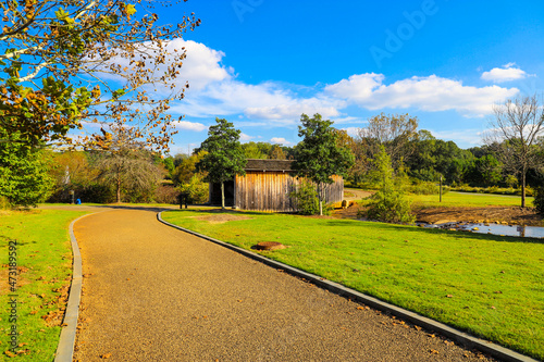 a shot of a wooden covered bridge over a river surrounded by lush green and autumn colored trees with lush green grass, blue sky and clouds at sunset at Garrard Landing Park in Alpharetta Georgia USA photo