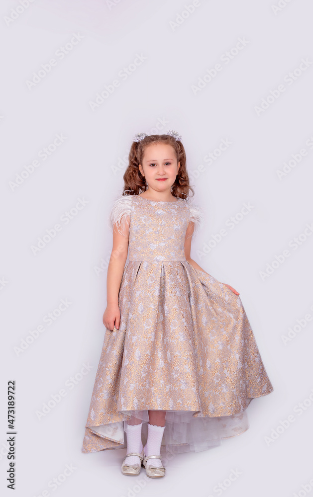 A happy little school-age girl in a long chic expensive dress, isolated on a white background. Full-length photo A happy little school-age girl in a long chic expensive dress, isolated on a white background. Full-length photo