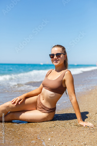 Summer lifestyle. Beautiful woman with a slim tanned body in a bikini swimsuit enjoying life and lying on the sand on the beach of a tropical island. Vacation