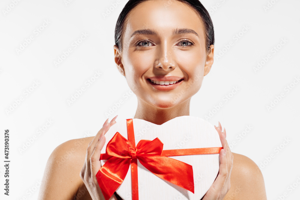 Portrait of a delighted young woman holding a heart-shaped red gift box on a white background Portrait of a delighted young woman holding a heart-shaped red gift box on a white background