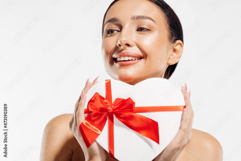 Portrait of a delighted young woman holding a heart-shaped red gift box on a white background Portrait of a delighted young woman holding a heart-shaped red gift box on a white background